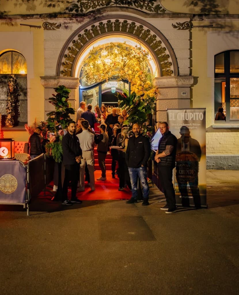 Eingang von LA MAISON bei Nacht mit floraler Beleuchtung